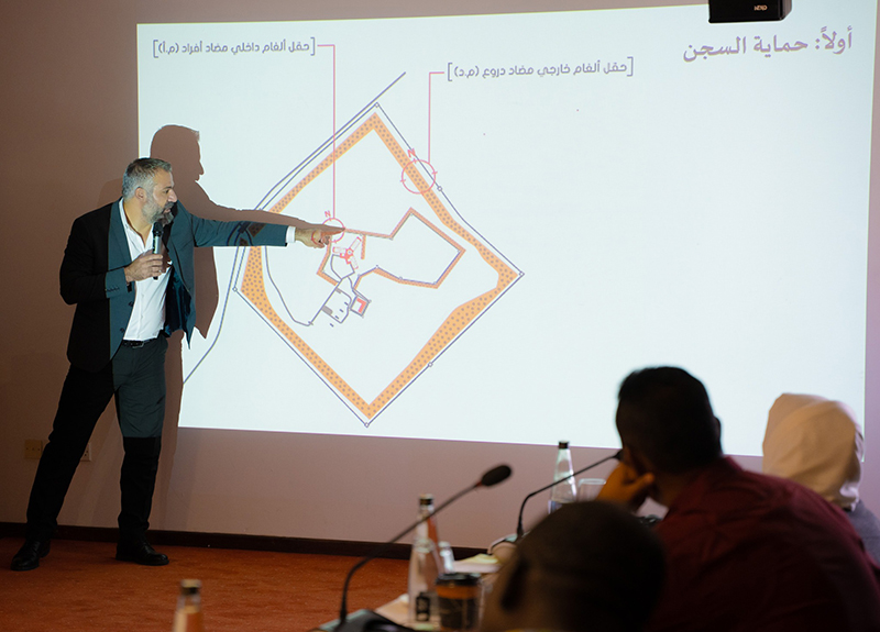 A man stands in front of a screen with a map projected on it and points to it