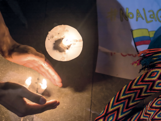 A person lights a candle during an anti-war protest in Barranquilla, Colombia.