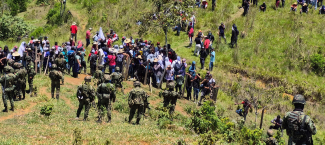 An aerial view of a group of soldiers interacting with a large civilian crowd in a rural setting