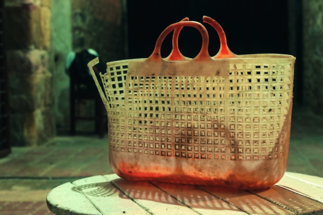 A worn, pink plastic basket sits on top of a small table in a dark room.