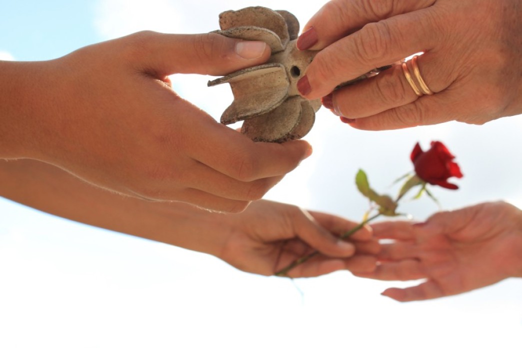 Image of an old woman who lost her husband during the war offers a symbolic memento to a young girl, who gives her a red rose in return.