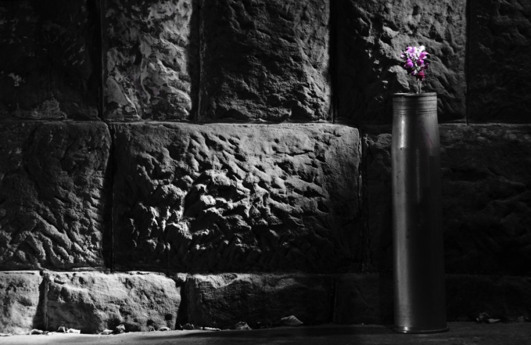 Image of empty bomb shell displayed in salon as a vase for artificial flowers.