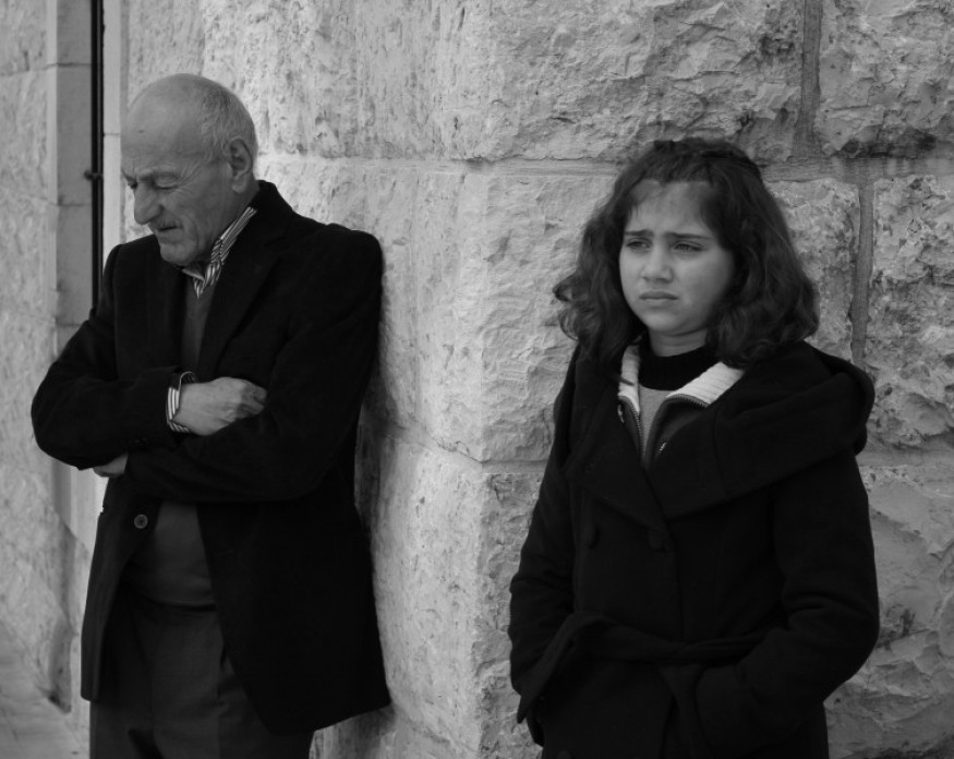 Black and white image of an elderly man and a child separated by a wall